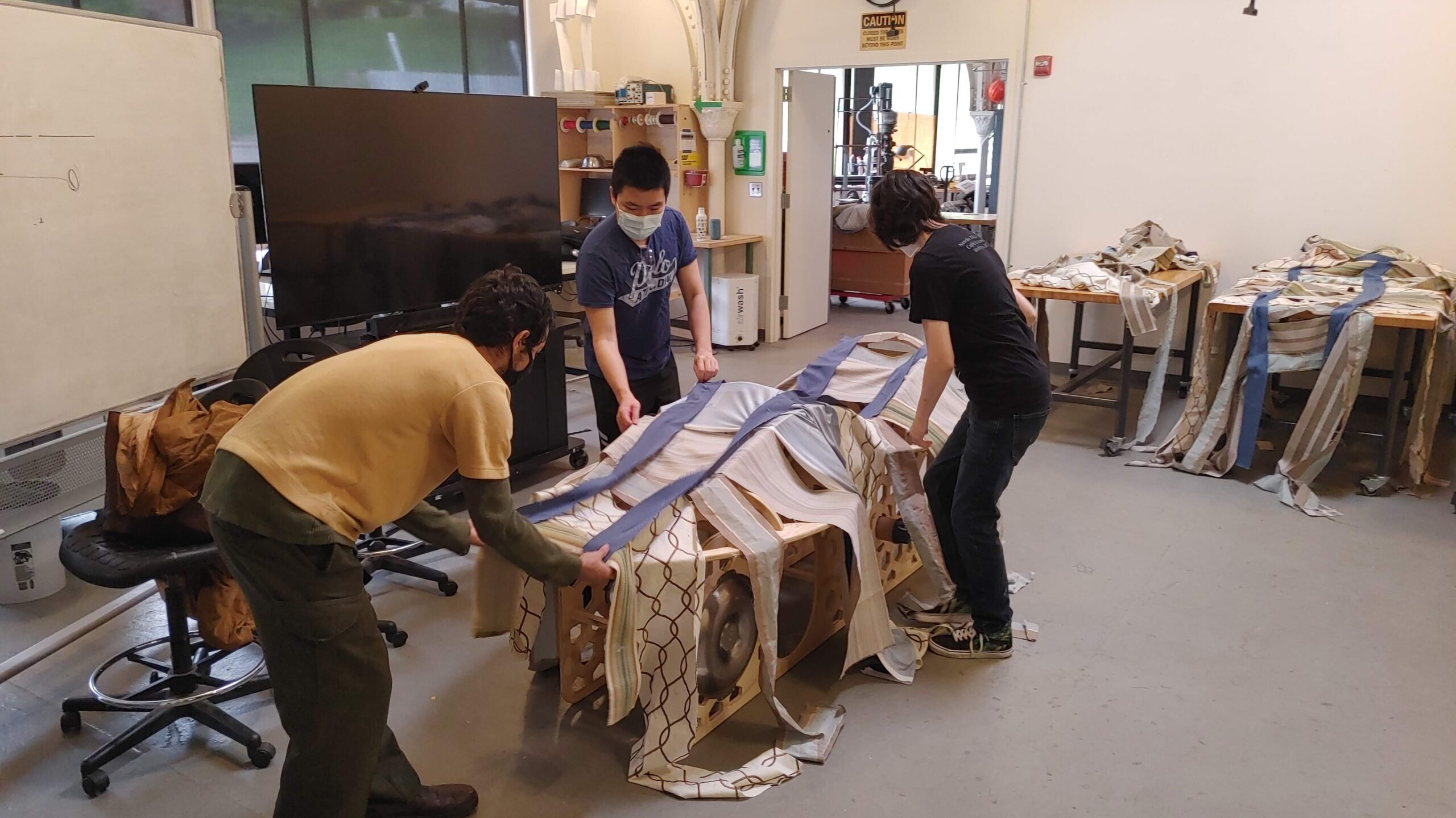 Image of Kyle, Austin, and Sam, applying fabric to the chassis.